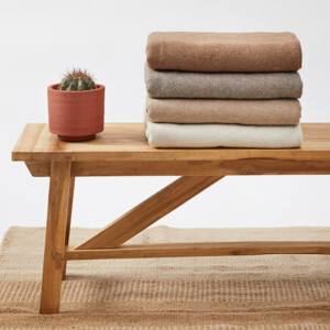 Holzbank mit verschiedenen Decken gefaltet und Kaktus