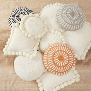 Gemütliche Anordnung von Kissen in verschiedenen Formen auf Teppich